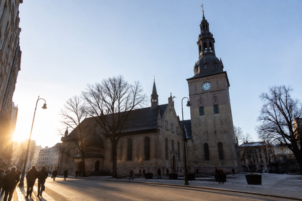 Stone cathedral with a tower beside a city street with pedestrians