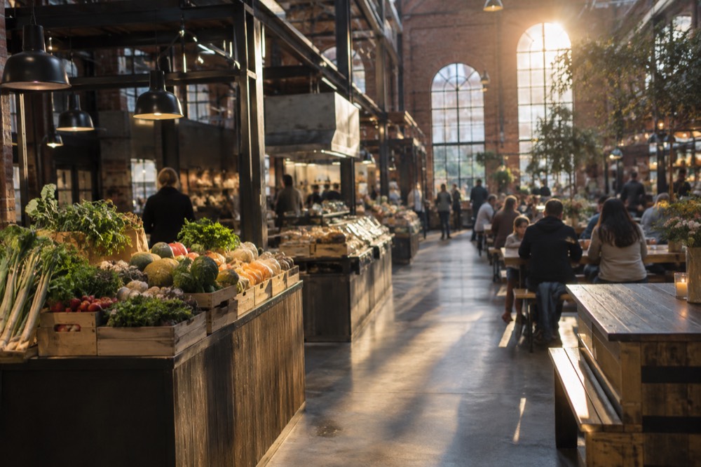 Families and visitors sharing food at long communal tables in a bright food hall