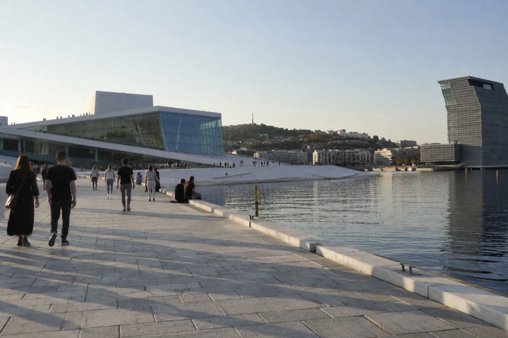 Pedestrians on the waterfront promenade between the Opera House and the MUNCH museum