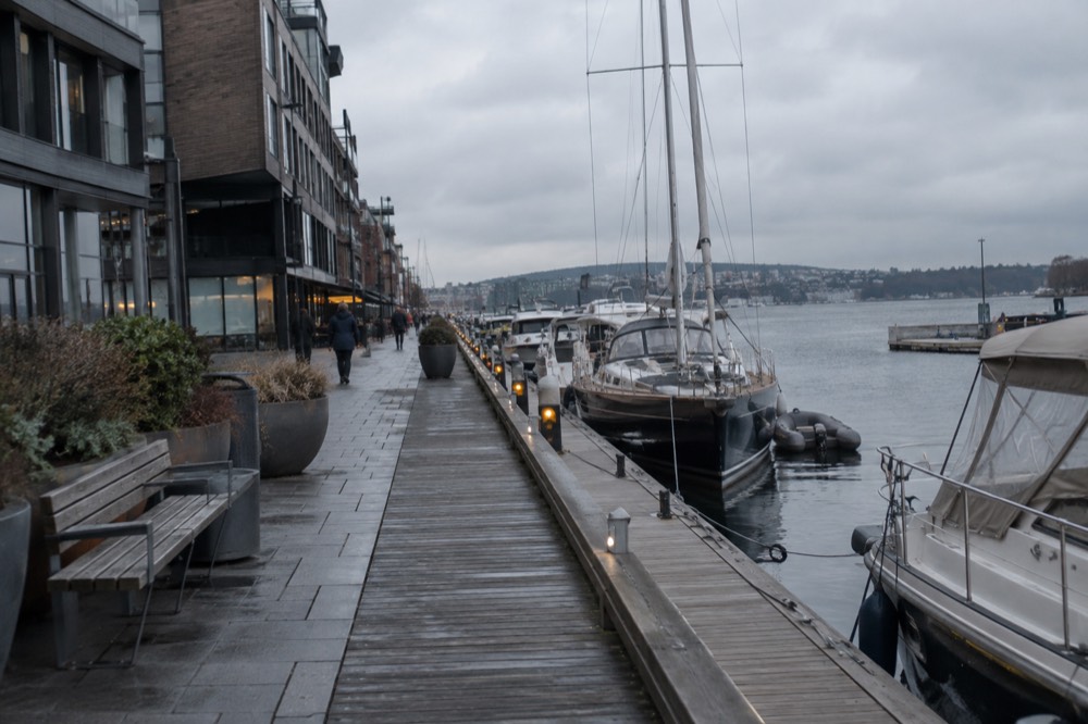 The Oslofjord waterfront promenade near Aker Brygge with moored boats and modern buildings