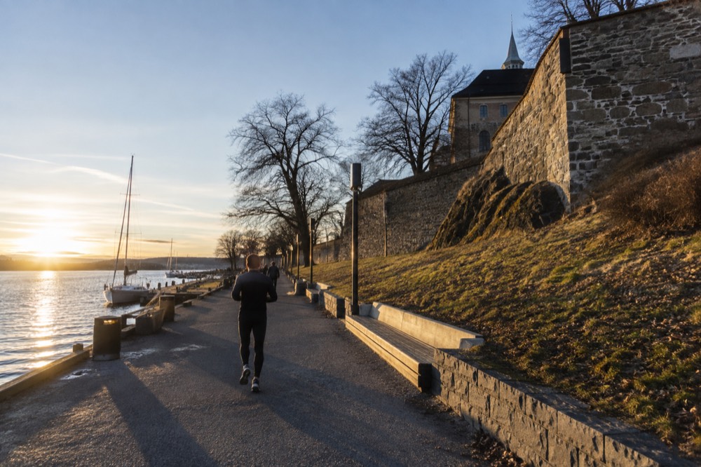 The Oslo waterfront promenade with the fortress walls rising above it in afternoon light