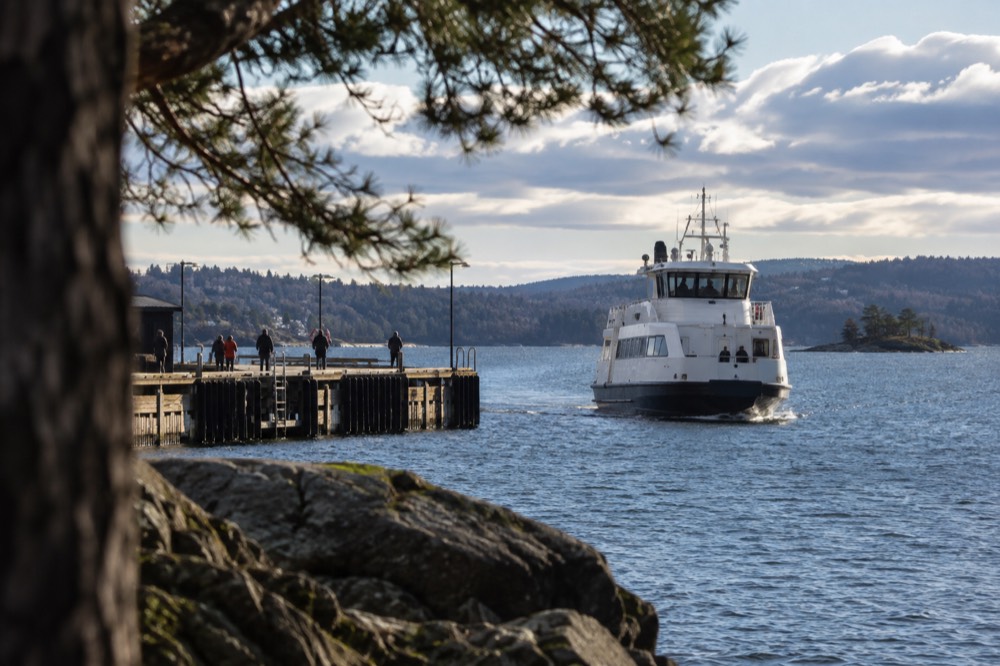White passenger ferry approaching a wooden pier on a peninsula in Oslo