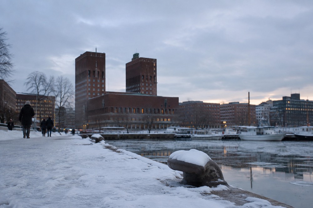 Oslo City Hall towers in winter dusk light above the frozen harbor