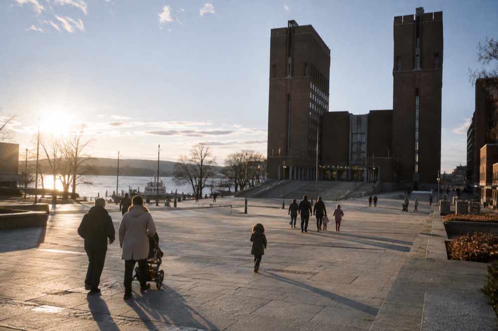 Families walking across the plaza in front of Oslo City Hall on a bright day