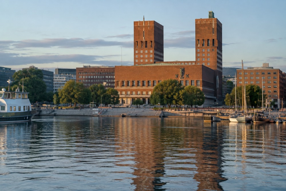 Oslo City Hall facade reflected in the harbor water at golden hour