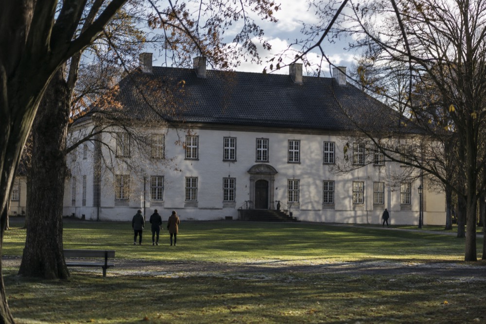 Historic manor facade with symmetric windows seen across a lawn