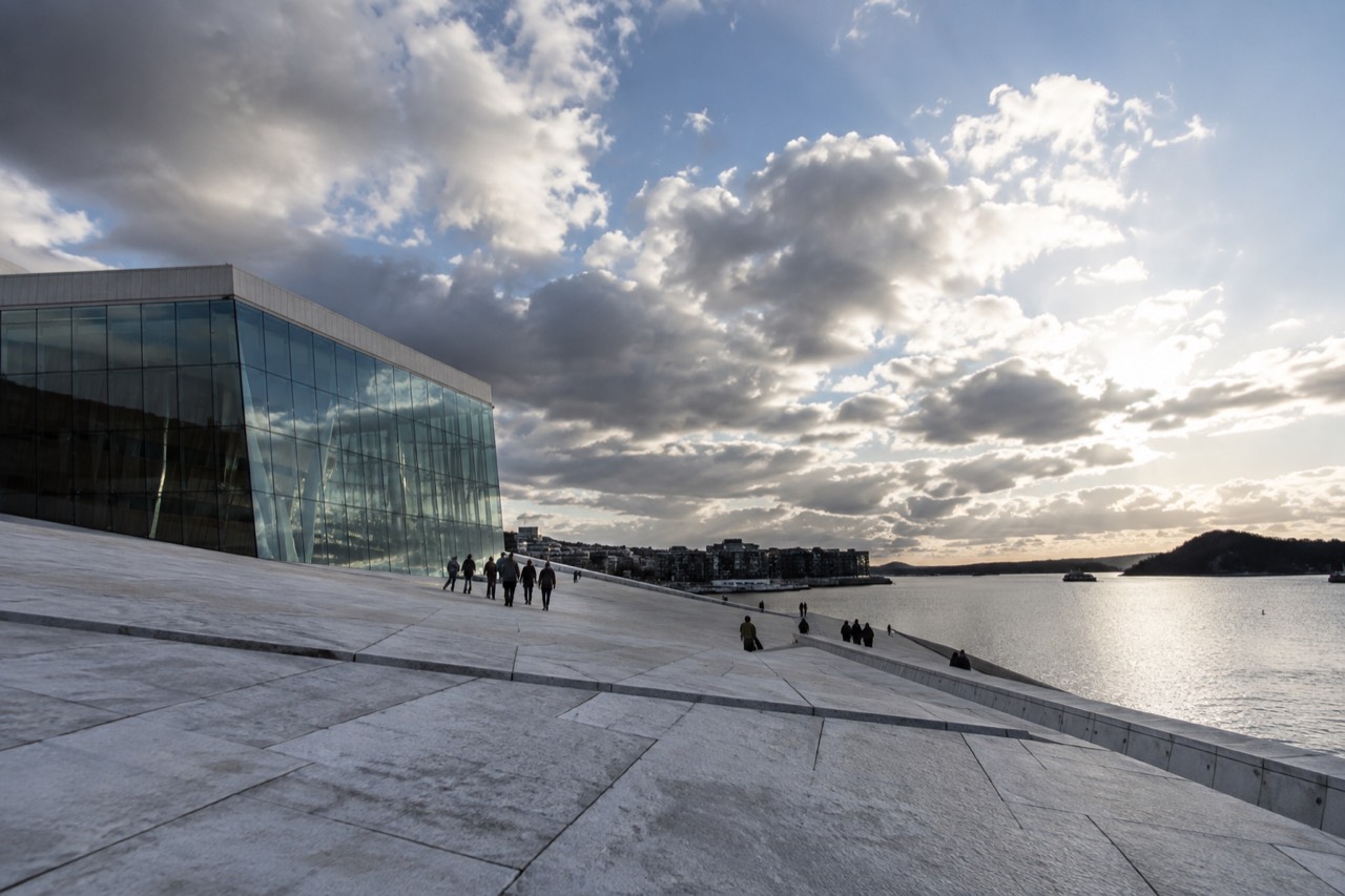 White marble slopes of the Oslo Opera House rising from the waterfront with the Oslofjord behind