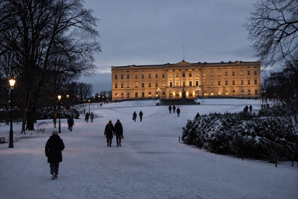 The illuminated Royal Palace facade in Oslo after dark with snow on the square