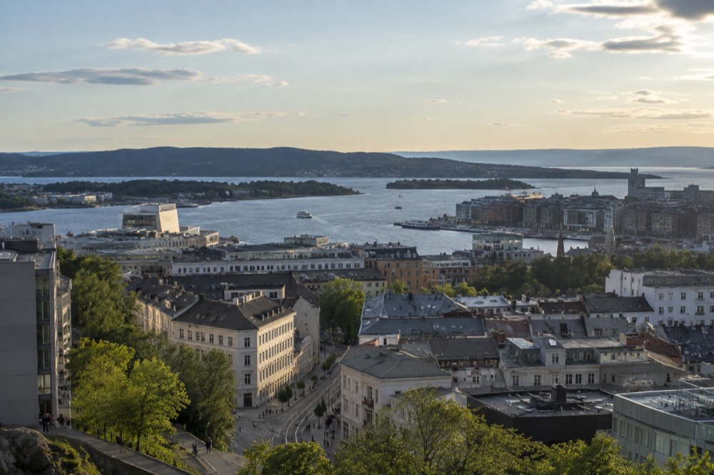 A wide view of Oslo city rooftops and fjord water from a high vantage point