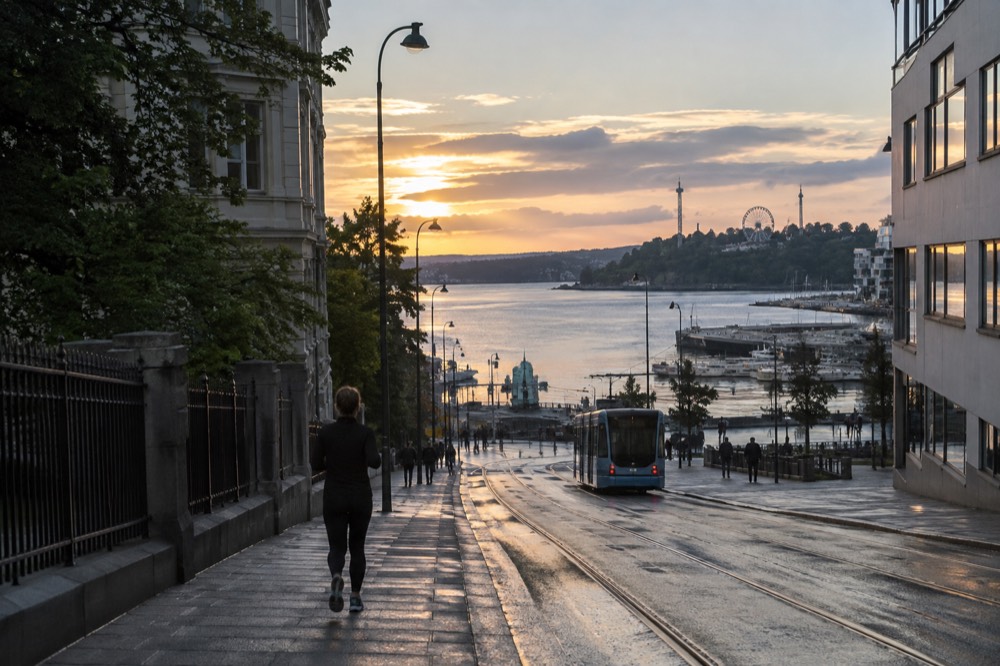 Evening light over a fjord inlet with amusement park rides silhouetted on a hillside