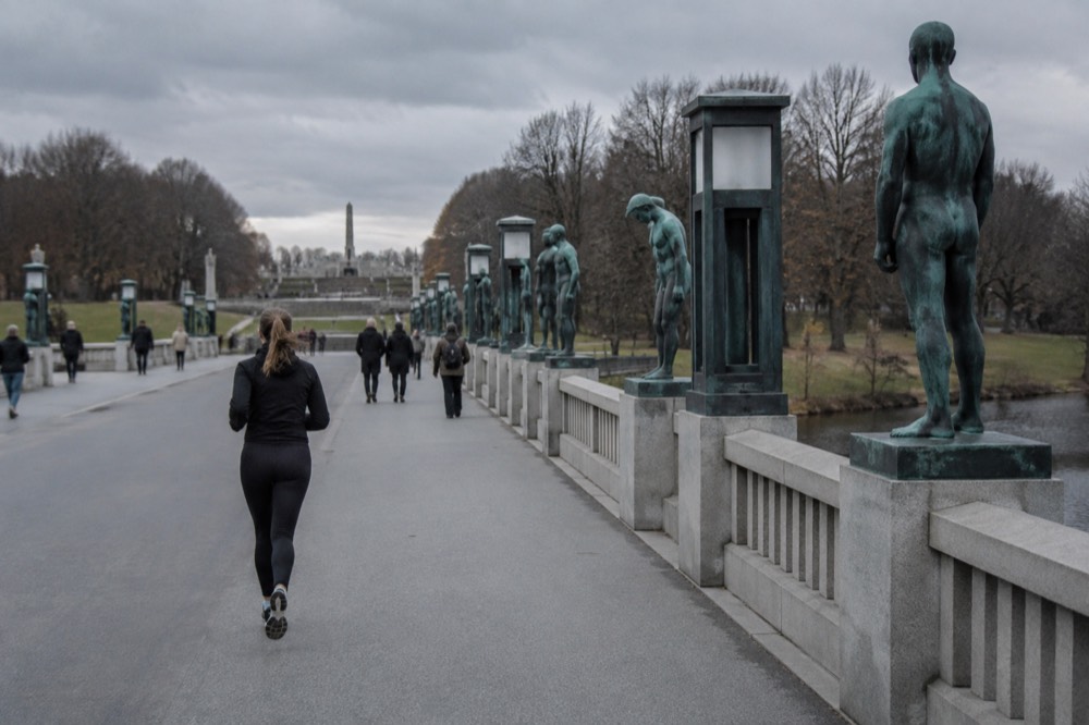 Bronze statues standing along the edge of a stone bridge over water