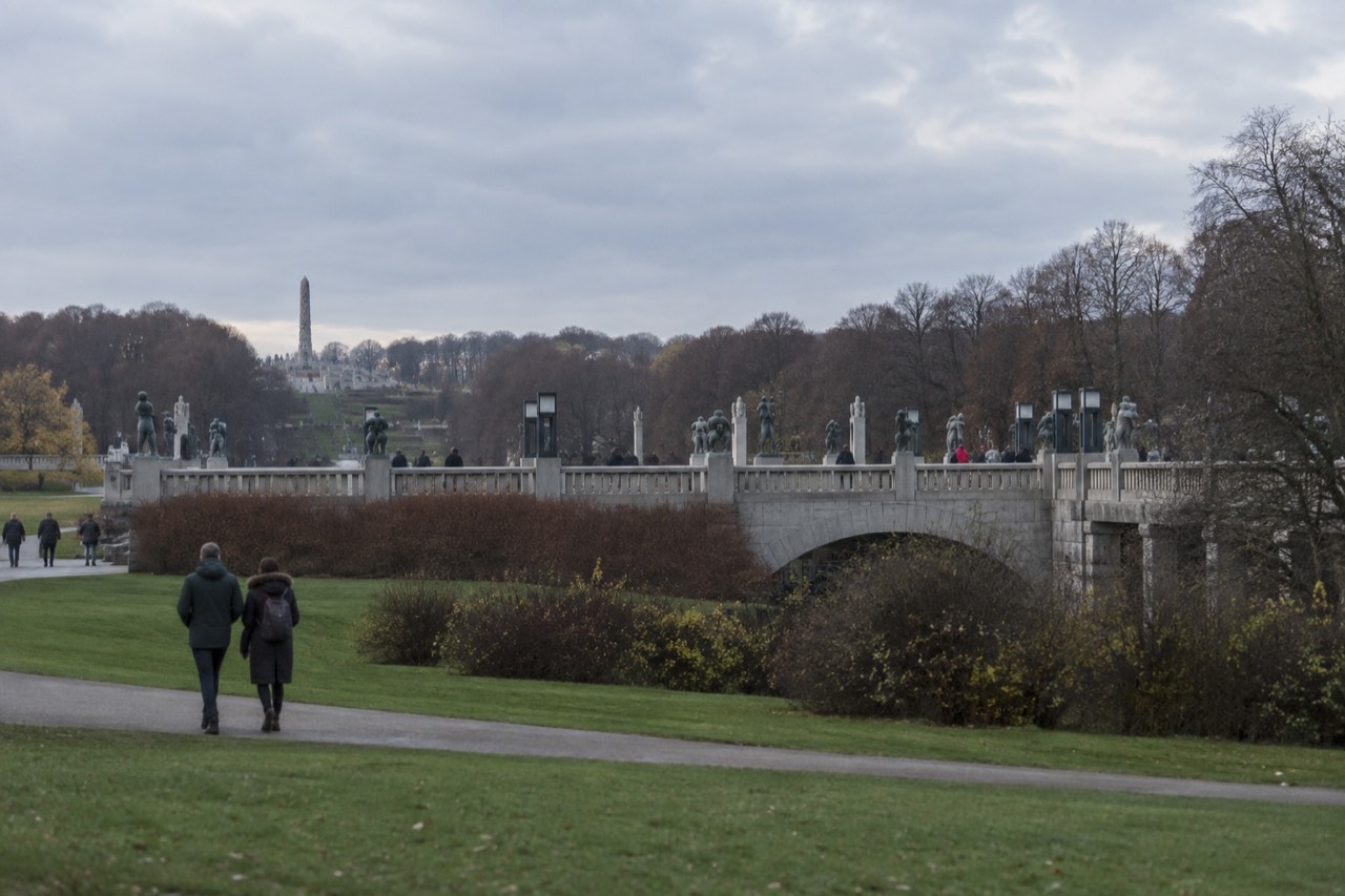 Stone sculptures lining a bridge in a green park under a wide sky