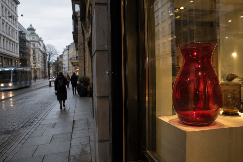 A red glass vase glowing under lights in a glassworks exhibition hall