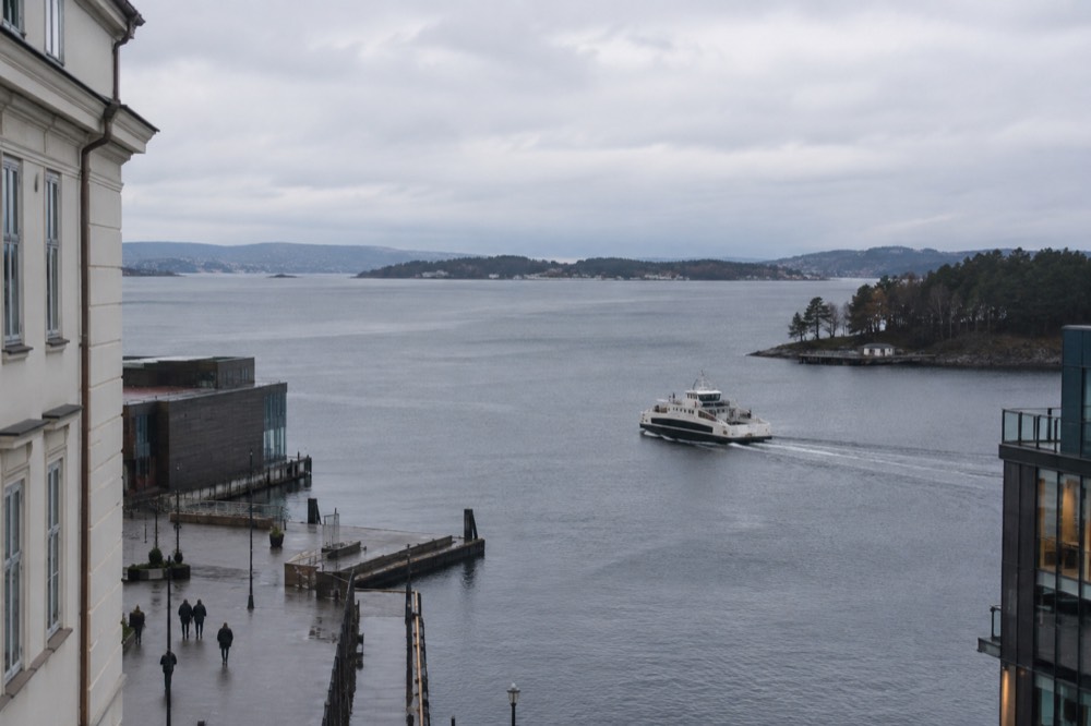 Small public ferry approaching a wooded island pier in the Oslofjord