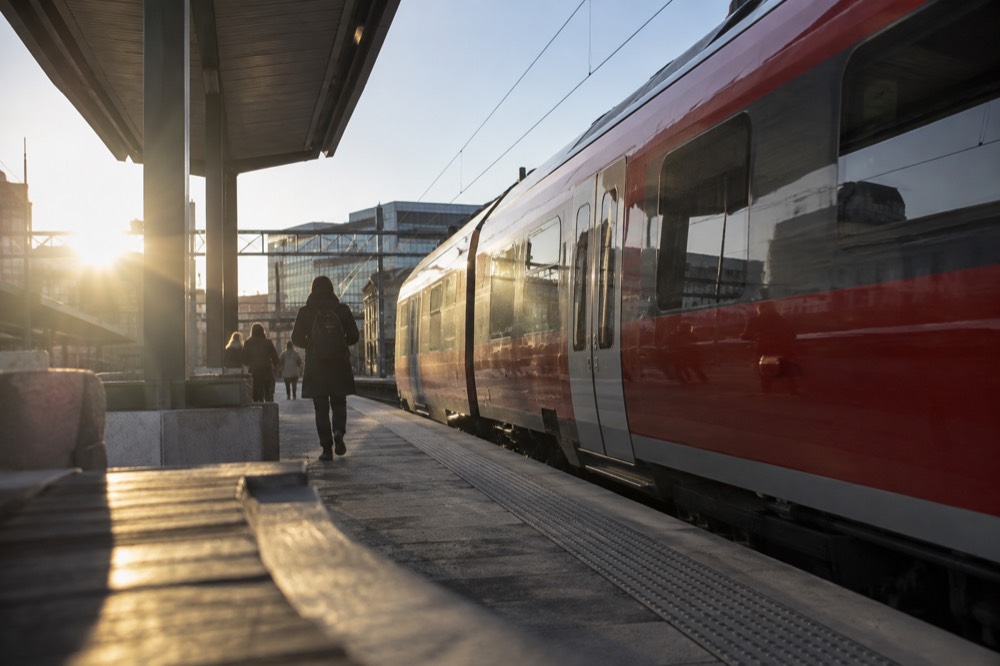 Red regional train at a platform in a Norwegian station under a clear sky