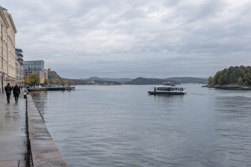 Quiet electric boat gliding across calm fjord water between green islands