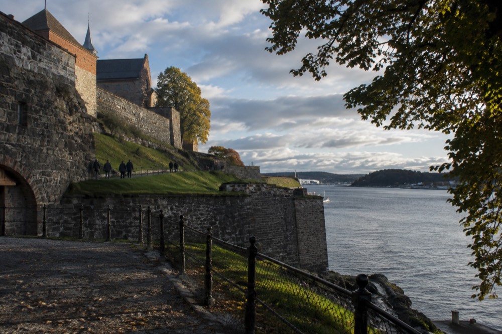 A stone fortress on a small island with trees and a narrow channel of water beside it