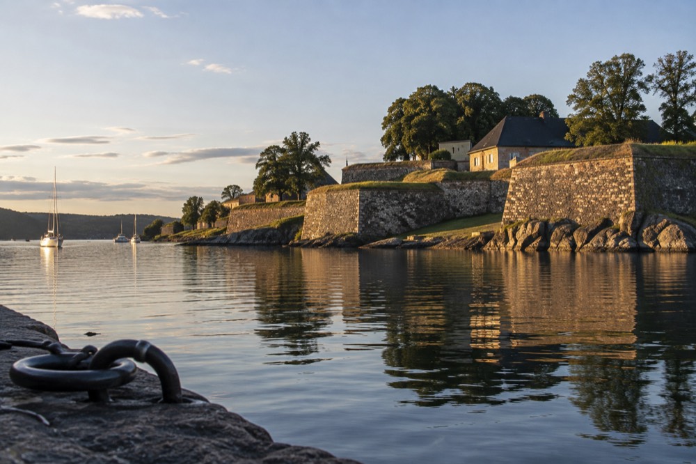 Star-shaped fortress ramparts reflected in a calm river at golden hour