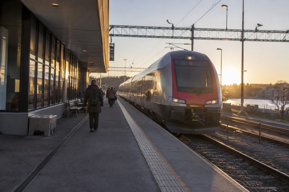 Regional train waiting at a platform beside a modern Norwegian station building