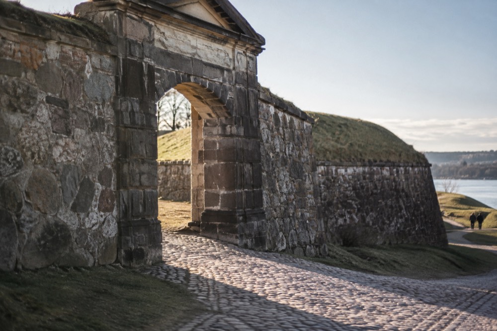 Stone gate and rampart wall with grass-covered earthworks beyond