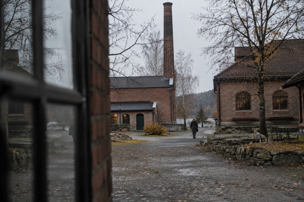 The old industrial yard of a glassworks village in autumn with brick buildings and bare trees