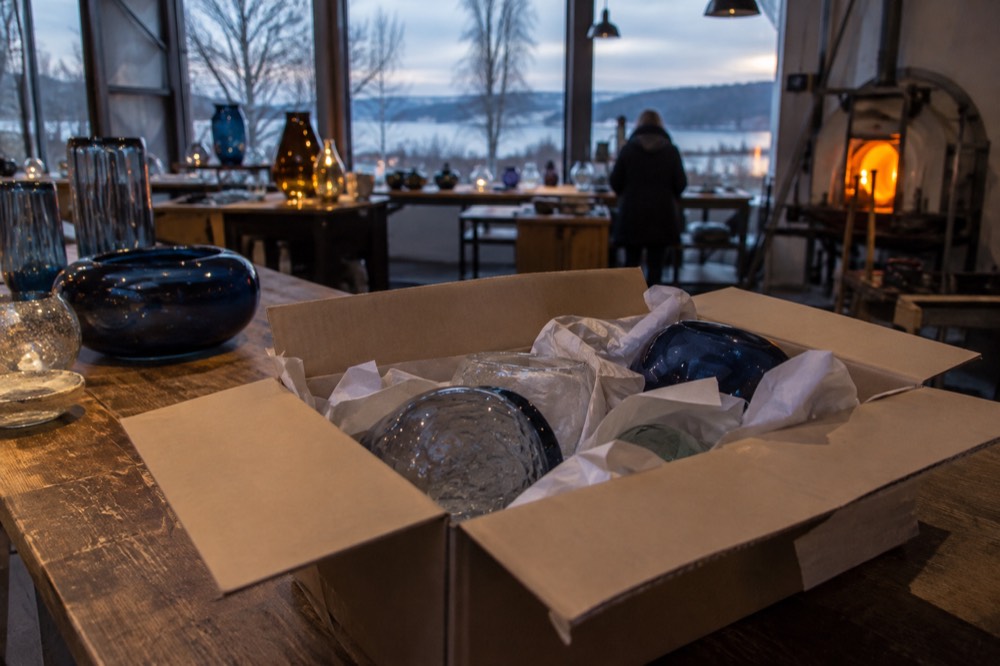Wrapped glass pieces in a cardboard box ready for travel on a wooden counter