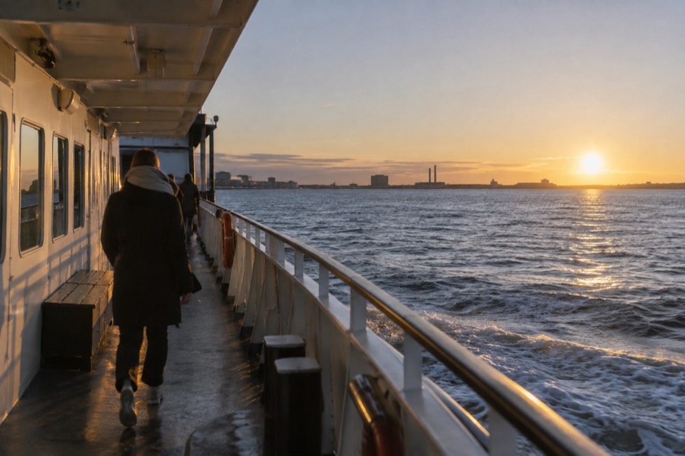 A passenger ferry moving through open water with low coastline on the horizon