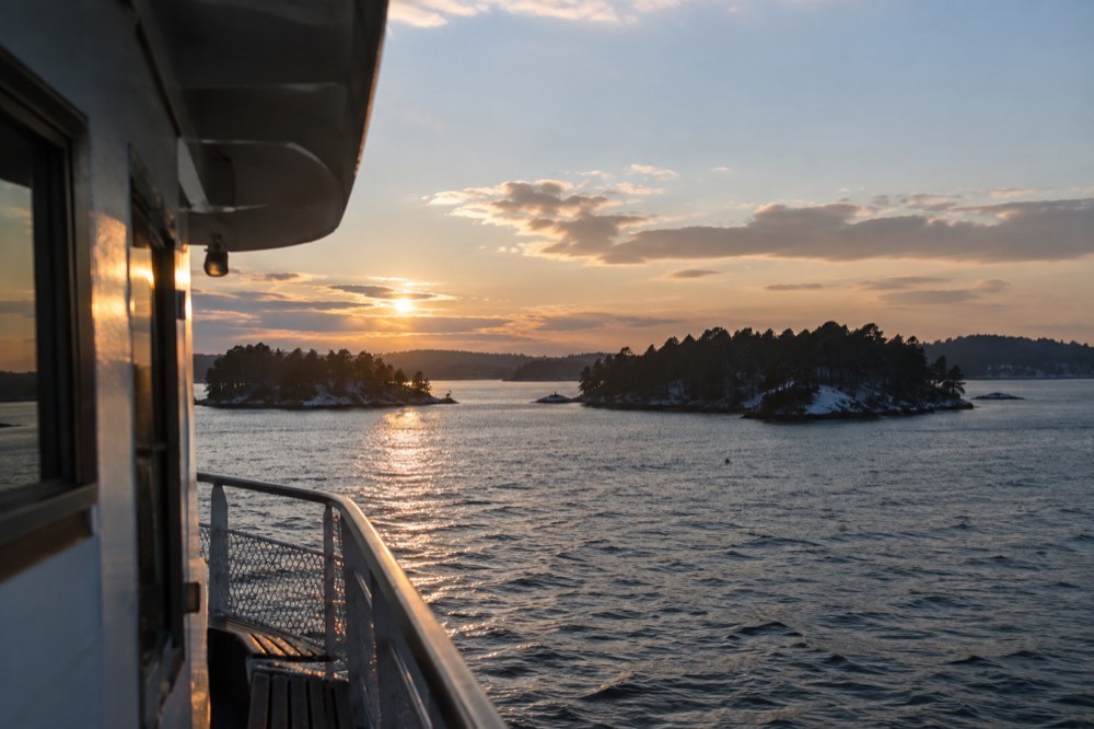 Small tree-covered islands in the Oslofjord seen from the water at golden hour