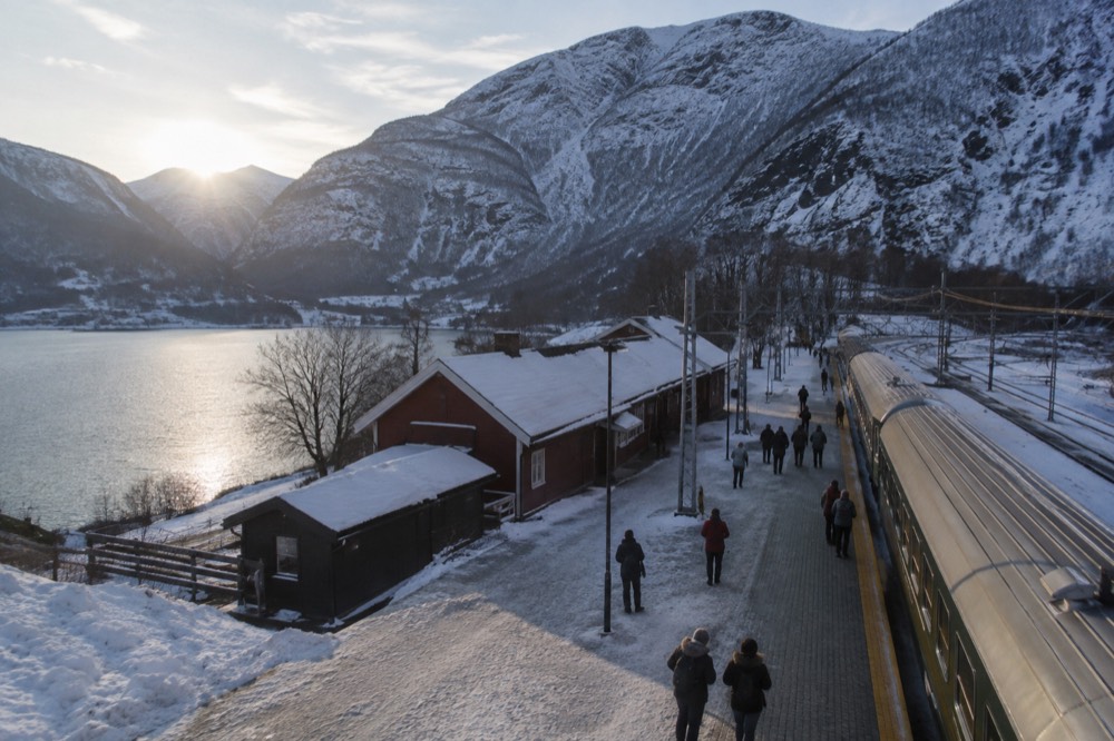 A train platform in a mountain station with snow-dusted peaks above the tracks