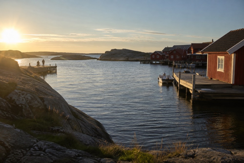Smooth granite coastline with red boathouses along the Bohuslan shore