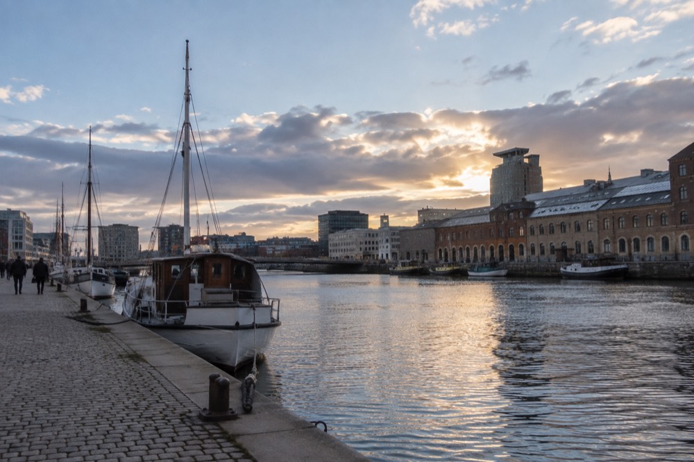 Evening light over a canal with moored boats and old warehouses