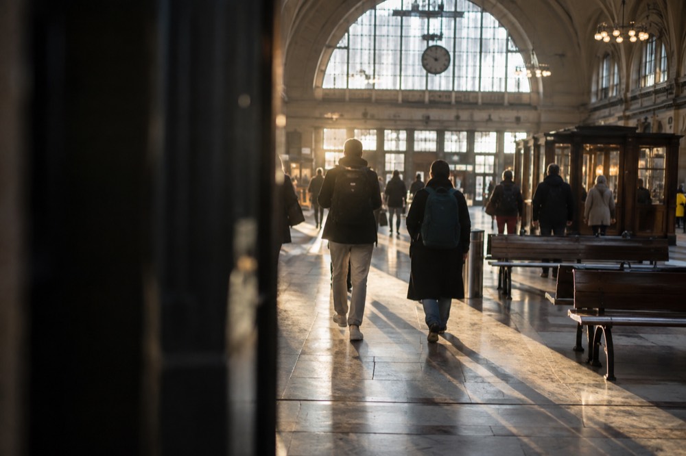 Travelers with backpacks walking through a grand railway station concourse