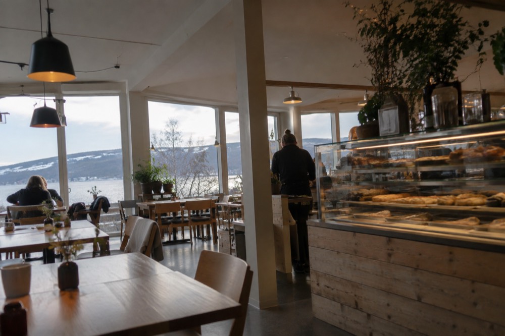 A cafe interior with wooden tables and a counter of pastries