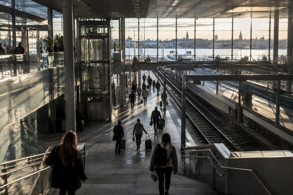 Modern station concourse with travellers walking toward departure platforms
