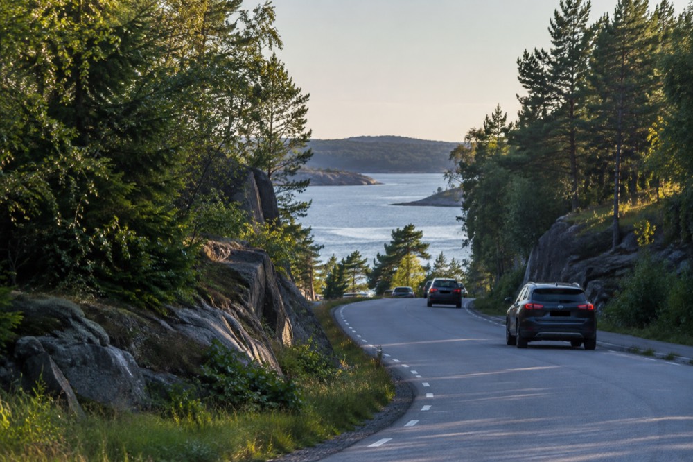 Forest road winding toward a border crossing between Norway and Sweden