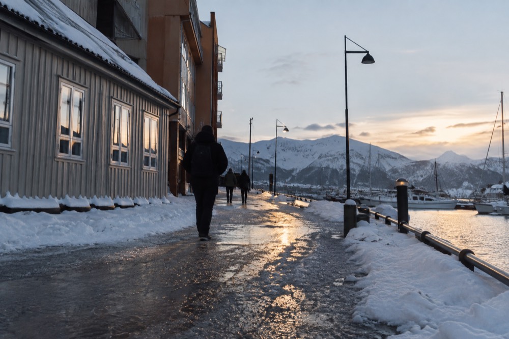 Winter street scene with warm lights reflecting on snow in a Norwegian city center
