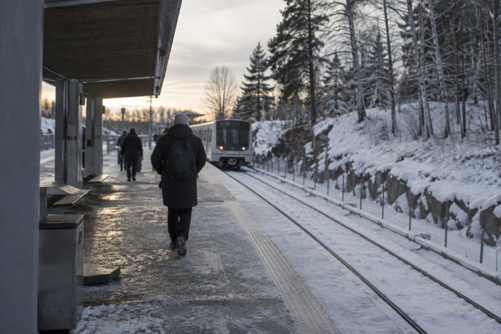 Metro platform at a forest-edge station with snow banks alongside the track