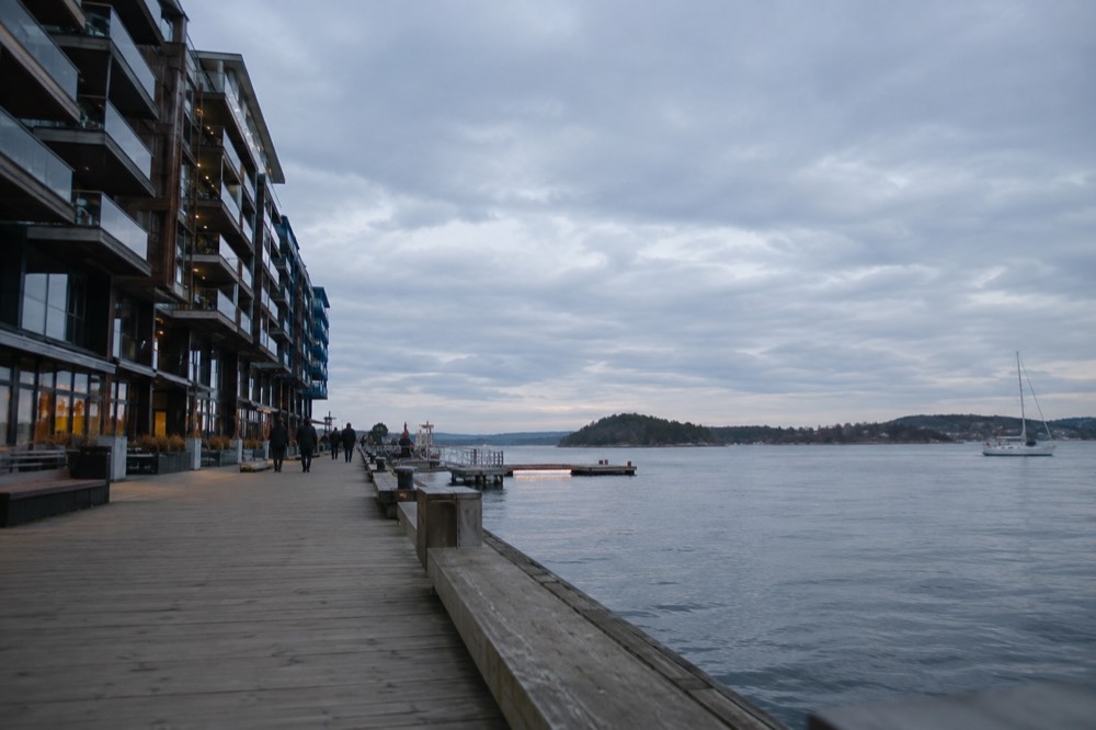 A calm Oslofjord with small wooded islands and low hills in the background
