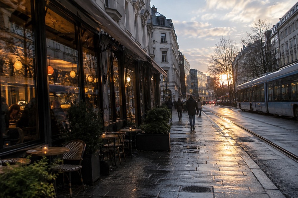 Warm light from bar windows reflecting on a wet Oslo street in the evening