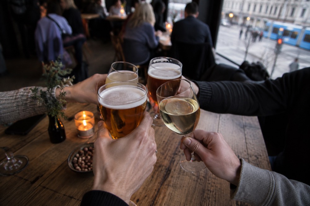 A group of glasses raised together over a wooden table in a cozy bar