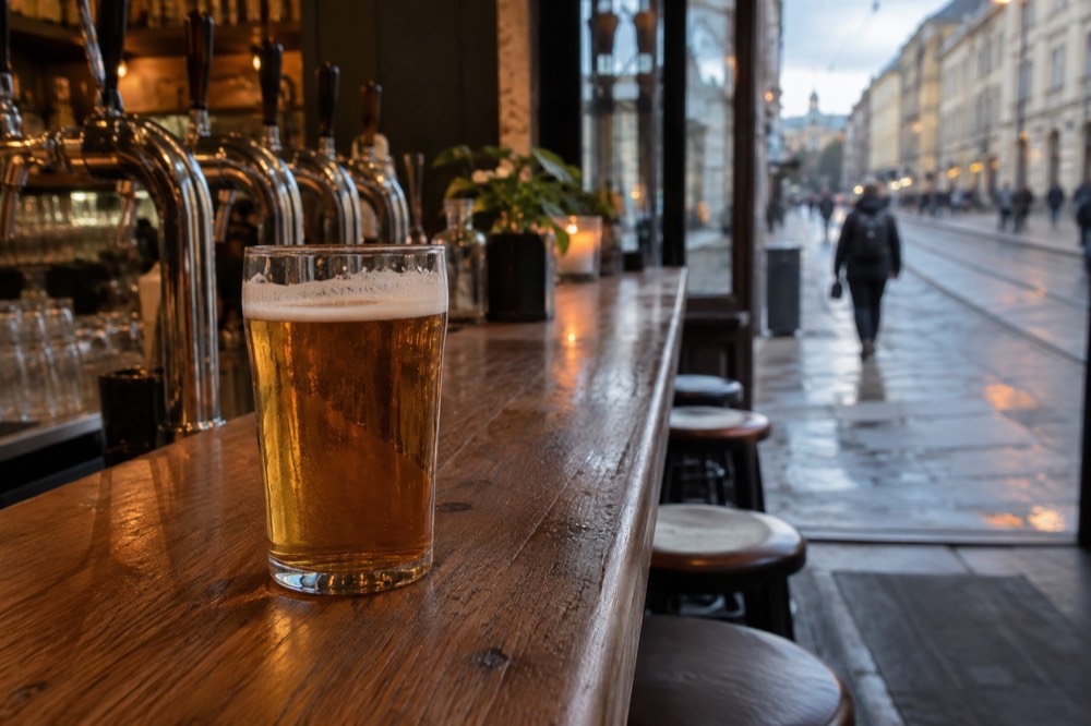 A glass of amber beer on a wooden bar counter with brewery taps behind