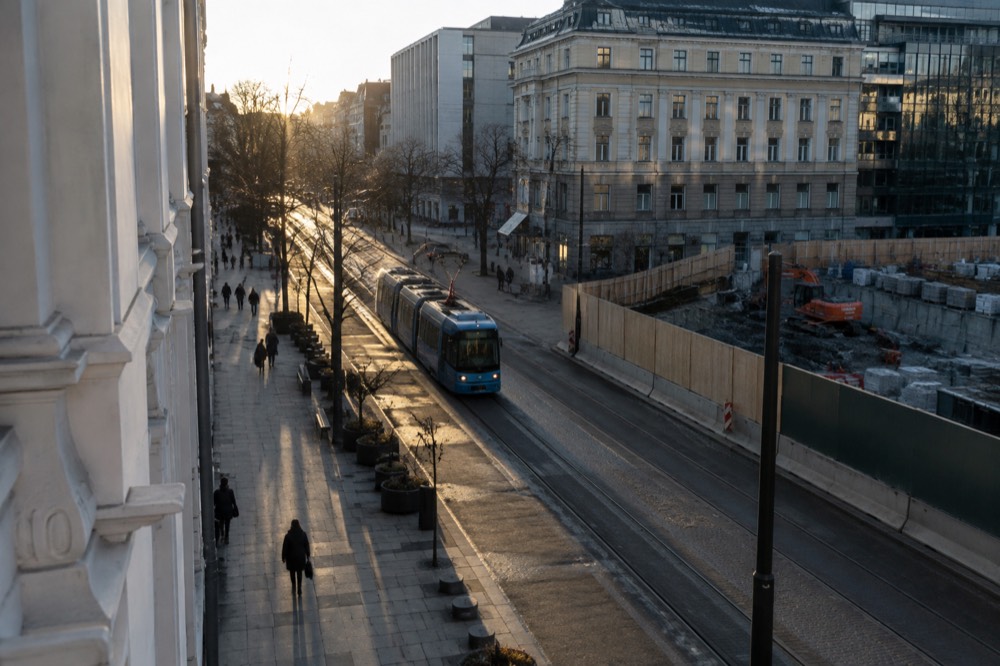 A construction hoarding with Norwegian signage along an Oslo street