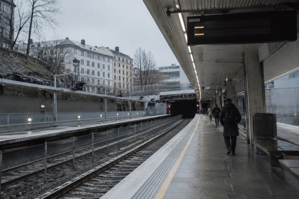 A metro platform in Oslo with an electronic departure display above the tracks