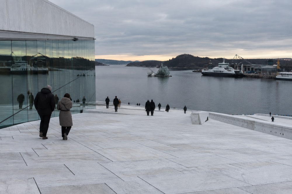 White marble opera house roof sloping down toward the water with moored boats