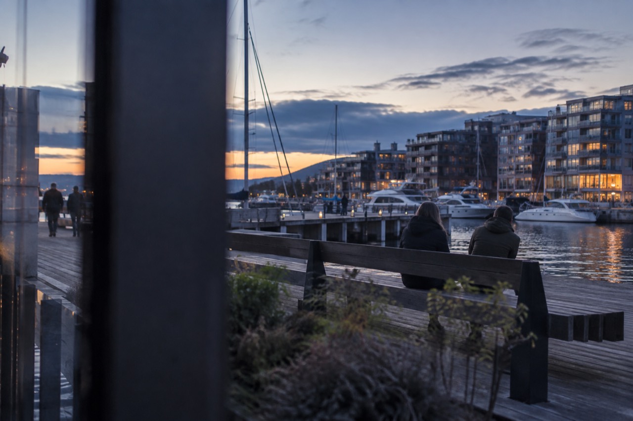 Aker Brygge waterfront in Oslo with moored boats and apartment buildings under a soft sky