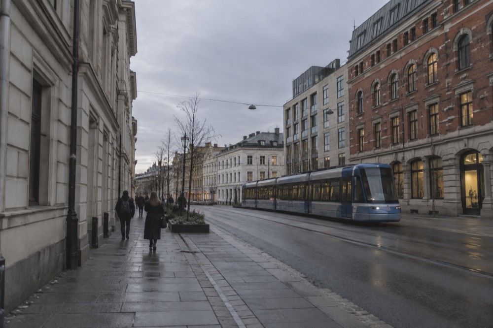 Oslo city street with people walking and a tram passing brick buildings