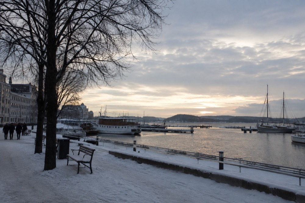 Snow-dusted Oslo waterfront with moored boats and pale winter sky