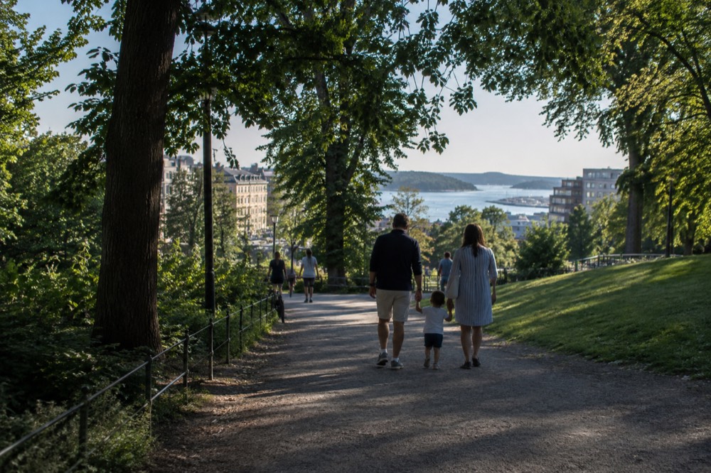 Family walking a wide Oslo park path in summer