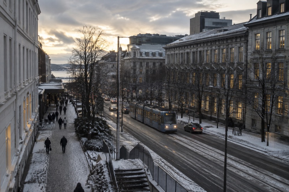 Snow-dusted street with warm window light in late afternoon darkness