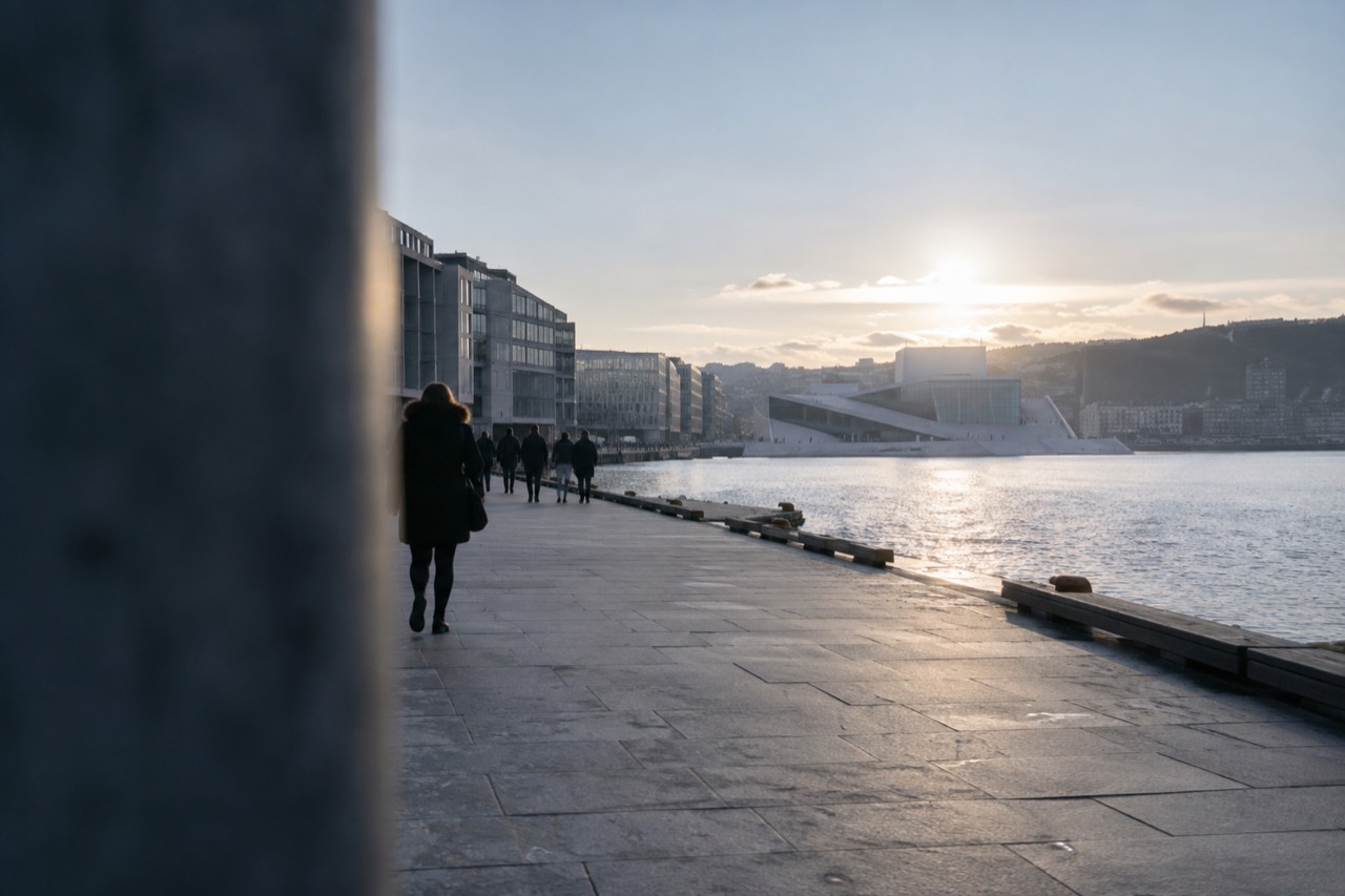 Wide flat waterfront promenade in Oslo with the Opera House in the distance